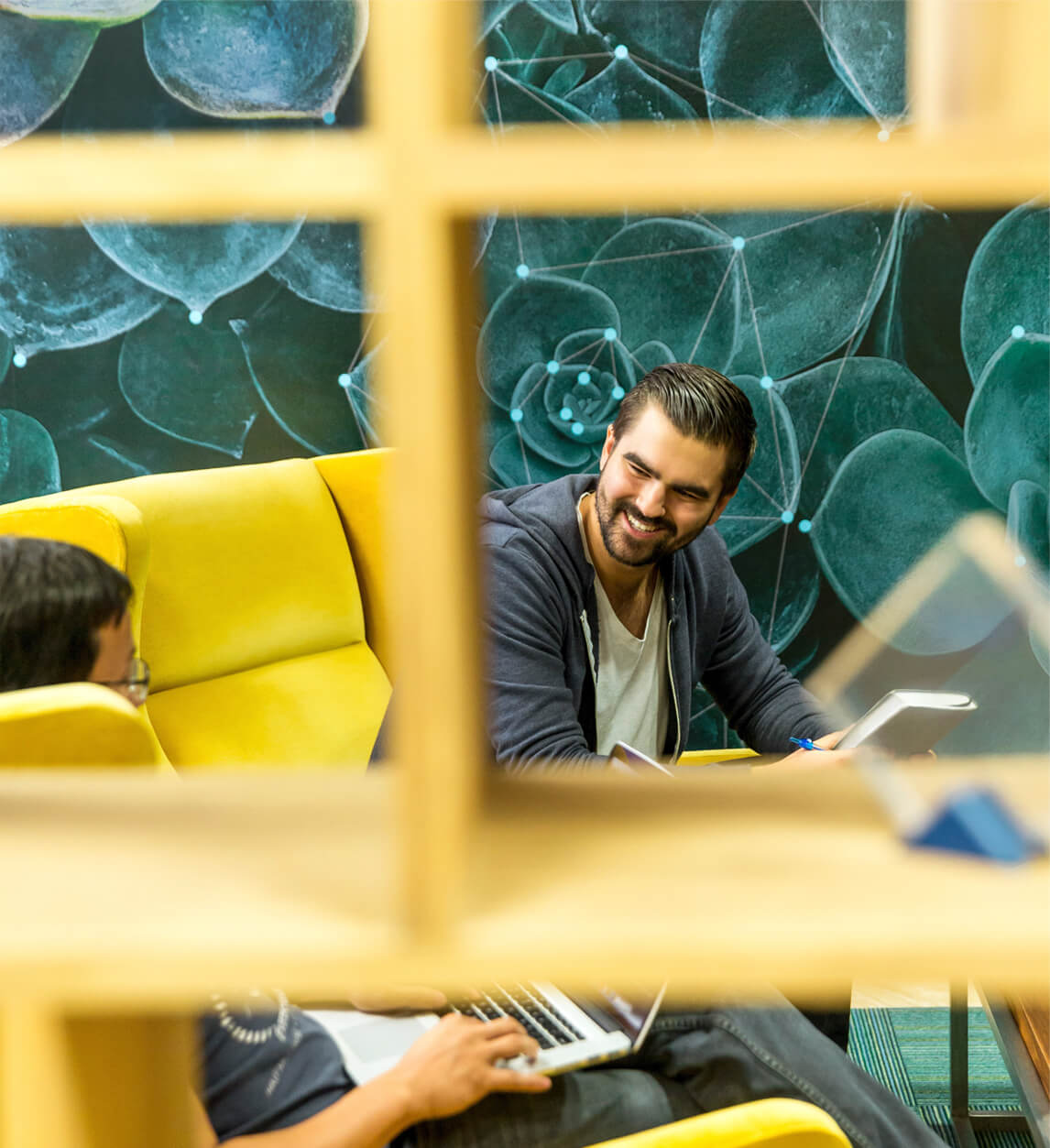 Two men sitting in comfortable chairs discussing a project.